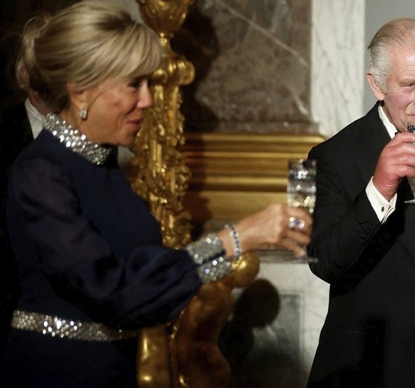 French President Emmanuel Macron, right, Britain's King Charles and Brigitte Macron toast during a state dinner in the Hall of Mirrors at the Chateau de Versailles in Versailles, west of Paris, W ...