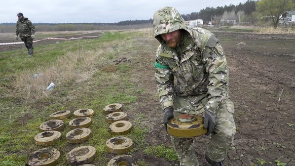 An interior ministry sapper collects mines on a mine field after recent battles in Irpin close to Kyiv, Ukraine, Tuesday, April 19, 2022. (AP Photo/Efrem Lukatsky)