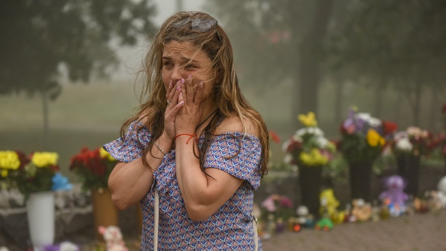 epa10039757 A woman cries near the flowers, brought to the destroyed Amstor shopping mall in Kremenchuk, Ukraine, 28 June 2022. At least 18 people died following Russian airstrikes on the crowded shop ...