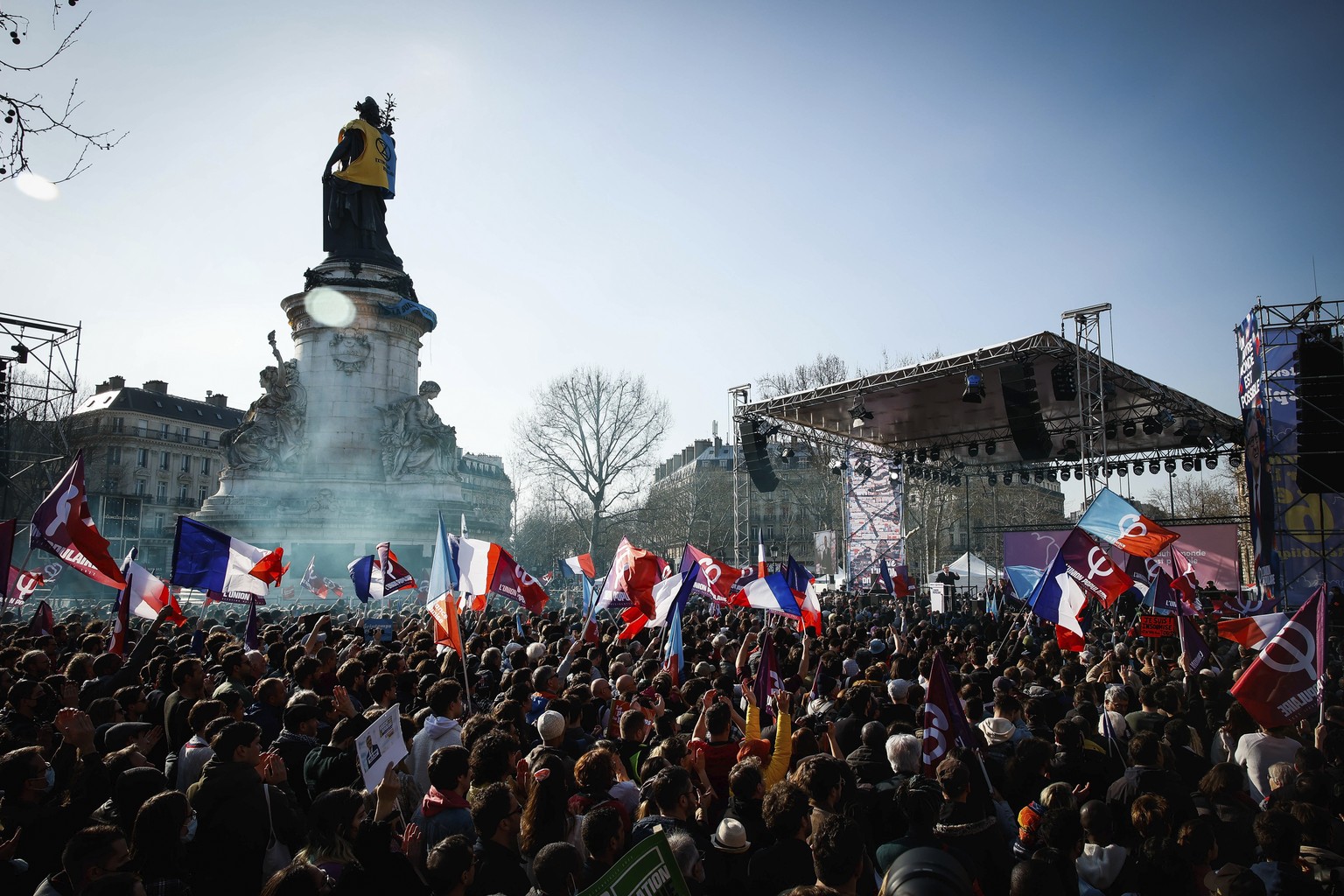 A crowd gather on Place deal Republique to listen to French far-left candidate for the upcoming presidential election Jean-Luc Melenchon delivers a speech after a march in Paris, Sunday, March 20, 202 ...