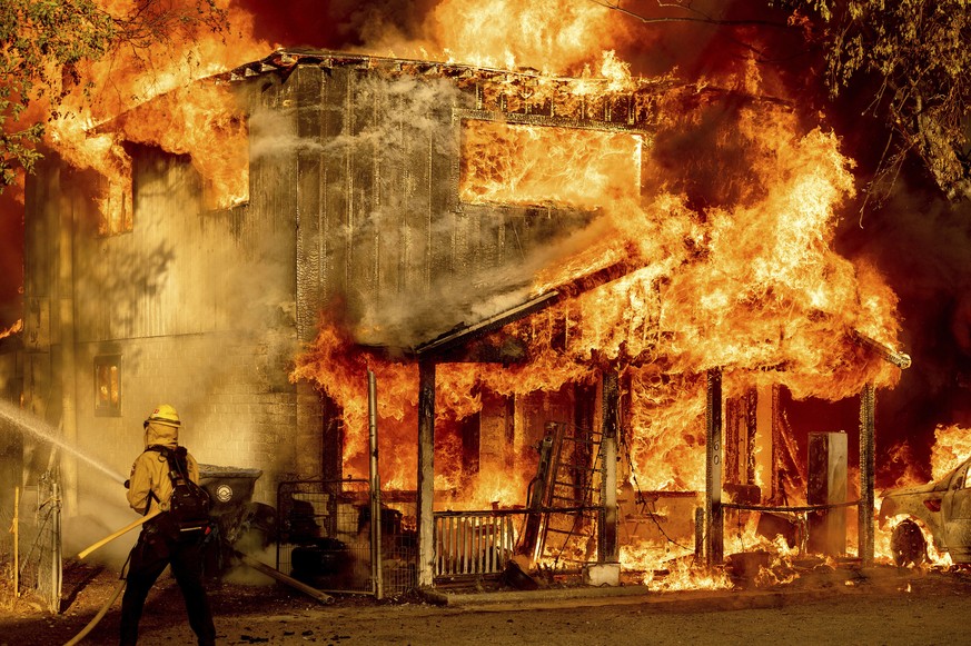 A firefighter sprays water while trying to stop the Sugar Fire, part of the Beckwourth Complex Fire, from spreading to neighboring homes in Doyle, Calif., Saturday, July 10, 2021. Pushed by heavy wind ...