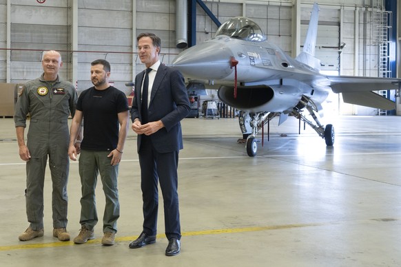 Ukrainian President Volodymyr Zelenskyy, center, a pilot, left, and Dutch caretaker Prime Minister Mark Rutte pose in front of a F-16 fighter jet in Eindhoven, Netherlands, Sunday, Aug. 20, 2023. The  ...