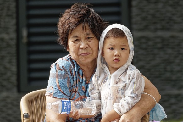 epa10102542 An elderly woman sits with a child in a public square in Shanghai, China, 02 August 2022. China&#039;s total fertility rate has dropped below 1.3 percent in recent years. The growth rate h ...