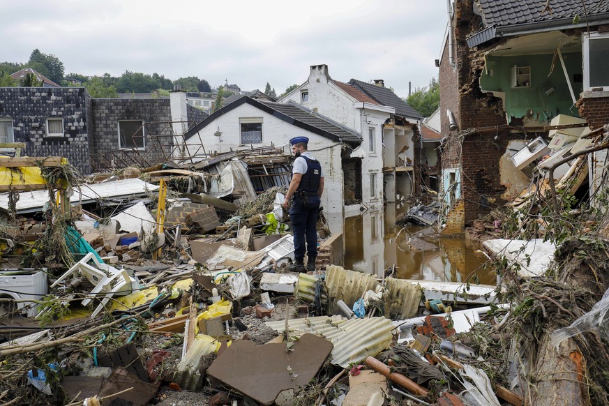 epa09350105 A police officer among the debris after heavy rains caused flooding in Pepinster, Belgium, 17 July 2021. Heavy rains have caused widespread damage and flooding in parts of Belgium. EPA/JUL ...