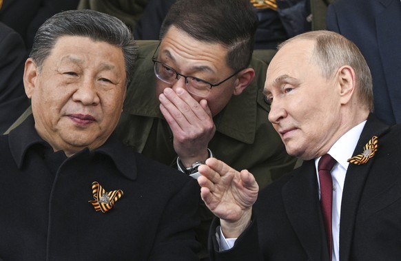 Russian President Vladimir Putin, right, and Chinese President Xi Jinping, left, talk as they watch the Victory Day military parade in Moscow, Russia, Friday, May 9, 2025, during celebrations of the 8 ...