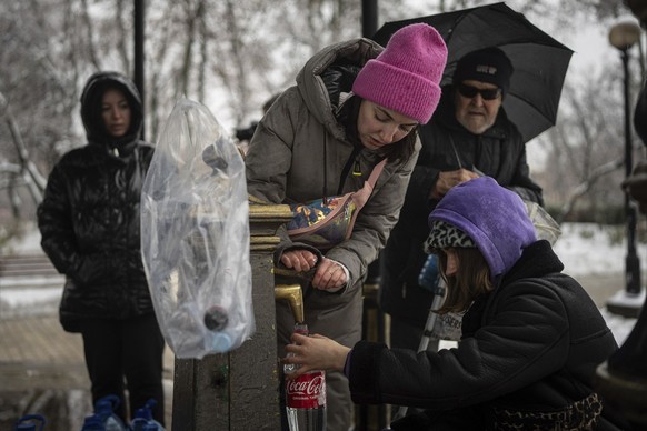 People collect water, in Kyiv, Ukraine, Thursday, Nov. 24, 2022. Residents of Ukraine&#039;s bombed but undaunted capital clutched empty bottles in search of water and crowded into caf