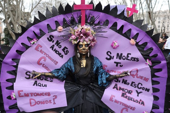 A woman parades with a writing reading 'If not now, when? If not here, where? If not you, who? If not with love and rebellion, how?' during a demonstration marking the International Women  ...