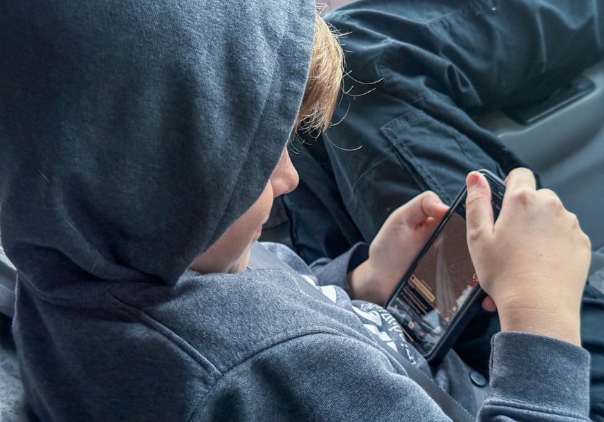 PORTSMOUTH, UNITED KINGDOM - OCTOBER 20: A 12-year-old boy looks at a iPhone screen on October 20, 2024 in Portsmouth, England. The amount of time children spend on screens each day rocketed during th ...