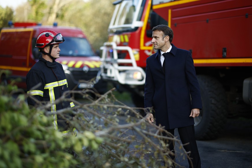 epa10956468 French President Emmanuel Macron (R) meets a firefighter during a visit after Storm Ciaran in Daoulas, France, 03 November 2023. At least one person died and at least 16 others were injure ...