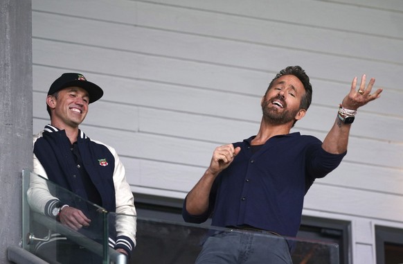 Wrexham co-owners Rob McElhenney, left, and Ryan Reynolds react in the stands as they watch the National League soccer match between Wrexham and Boreham Wood at The Racecourse Ground, in Wrexham, Wale ...