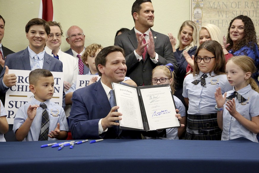 Florida Gov. Ron DeSantis displays the signed Parental Rights in Education, aka the Don&#039;t Say Gay bill, flanked by elementary school students during a news conference on Monday, March 28, 2022, a ...