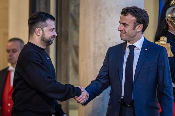 epa10628504 French President Emmanuel Macron (R) shakes hand with his Ukrainian counterpart Volodymyr Zelensky (L), upon his arrival for their meeting at Elysee palace in Paris, France, 14 May 2023. E ...