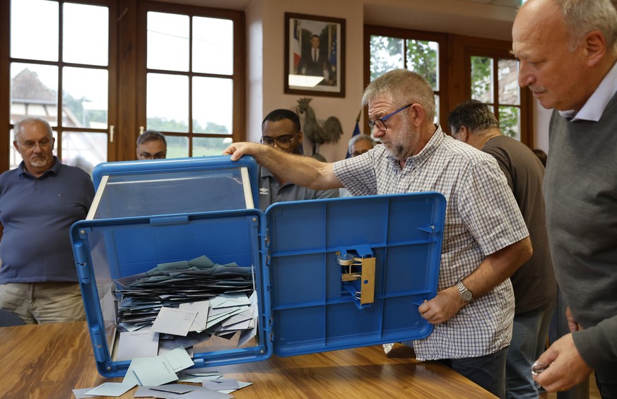 A voting assistant empty a voting box in a voting station in Soultz-Les-Bains, eastern France, Sunday, June 30, 2024. France is holding the first round of an early parliamentary election on Sunday tha ...