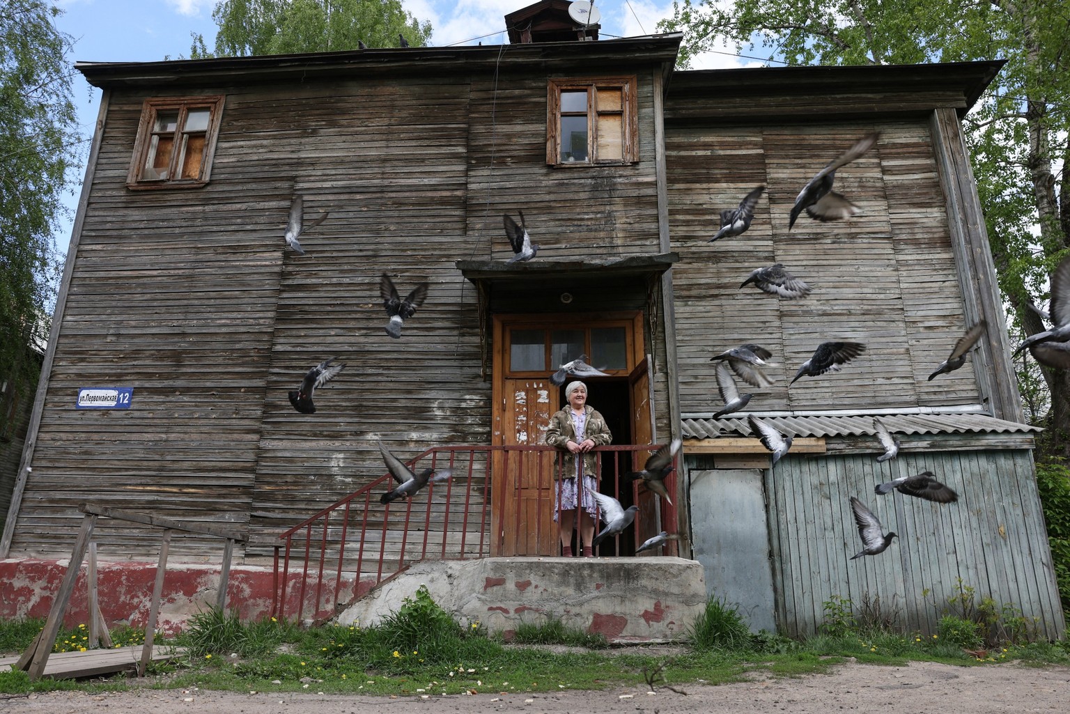 Local resident Tamara, the 65-year-old pensioner who worked in a now-closed fabric factory, stands at the entrance of a two-storey wooden communal apartments building she lives in, which was built for ...