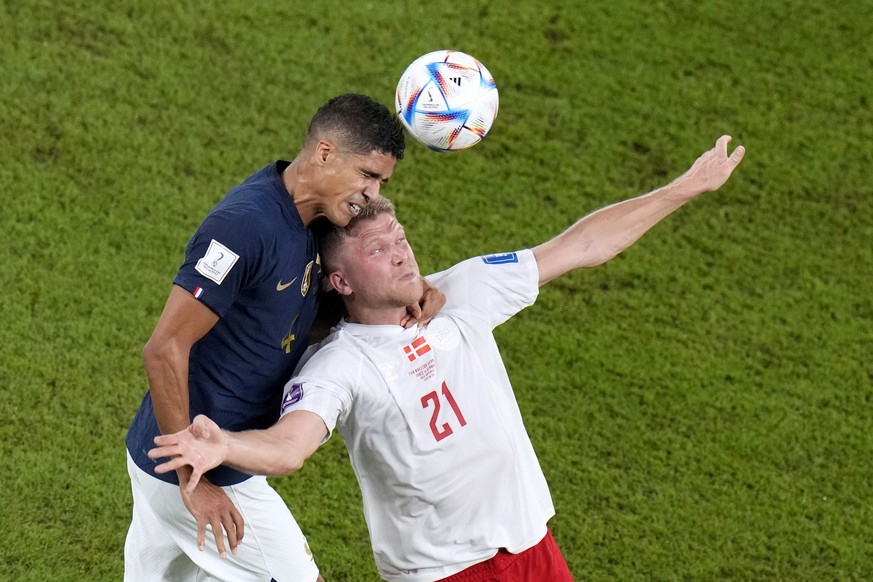 France's Raphael Varane, and Denmark's Andreas Cornelius, go for a header during the World Cup group D soccer match between France and Denmark, at the Stadium 974 in Doha, Qatar, Saturday, N ...