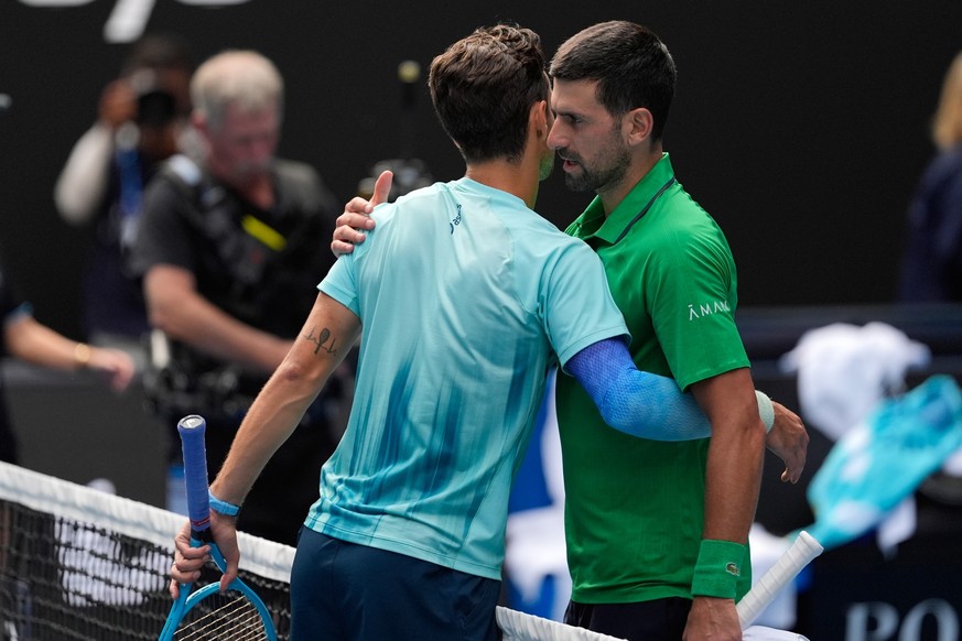 Lorenzo Musetti, left, of Italy embraces Novak Djokovic of Serbia after retiring from their quarterfinal match at the Australian Open tennis championship in Melbourne, Australia, Wednesday, Jan. 28, 2 ...