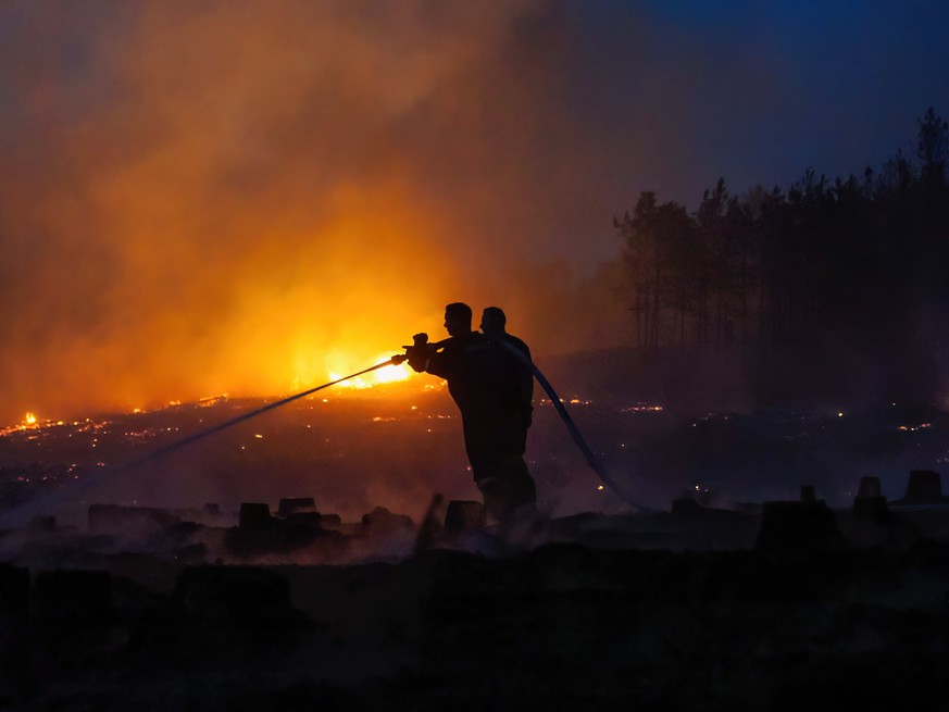 epa10070593 Hungarian firemen try to extinguish the flames of a forest fire near Soltszentimre, Hungary, late 13 July 2022. A person was killed by the fire that burned on some 50 hectares before it wa ...