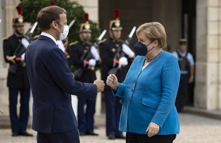 epa09472040 French President Emmanuel Macron (L) greets German Chancellor Angela Merkel (R) as she arrives for a meeting at the Elysee Palace in Paris, France, 16 September 2021. German Chancellor Mer ...