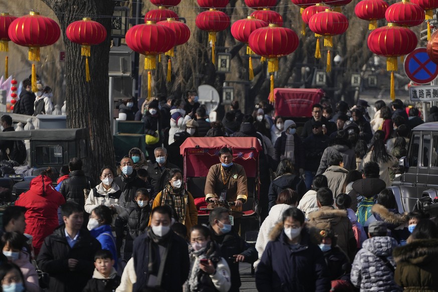 A trishaw driver wades through a crowded street at the frozen Houhai Lake in Beijing, Monday, Jan. 30, 2023. Chinese people are enjoying the Lunar New Year and visiting various tourist sites in cities ...