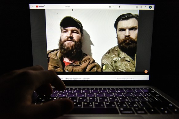 epa09934781 A video of a press conference from the Azovstal steel plant in Mariupol by Azov regiment servicemen Illia Samoilenko (R) and Sviatoslav Palamar (L) is seen on a computer screen in Kyiv, Uk ...