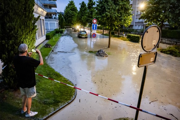 Une personne prend une photographie du debordement de la riviere la Morges sur une route suite a un orage qui a entraine une importante inondation dans le centre ville le mardi 25 juin 2024 a Morges.  ...