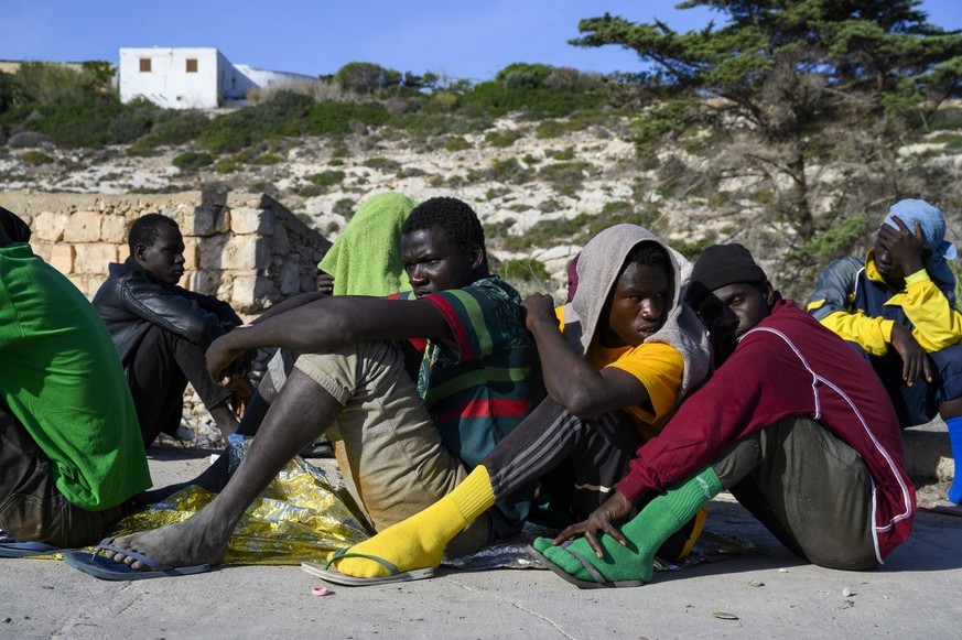 Migrants sit in Lampedusa Island, Italy, Friday, Sept. 15, 2023. Lampedusa, which is closer to Africa than the Italian mainland, has been overwhelmed this week by thousands of people hoping to reach E ...