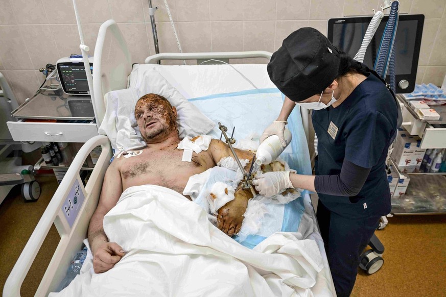 Un membre du personnel médical s'occupe d'un soldat blessé au bras et à la tête, dans le service de soins intensifs polytraumatologiques de l'hôpital Mechnykov de Dnipro.