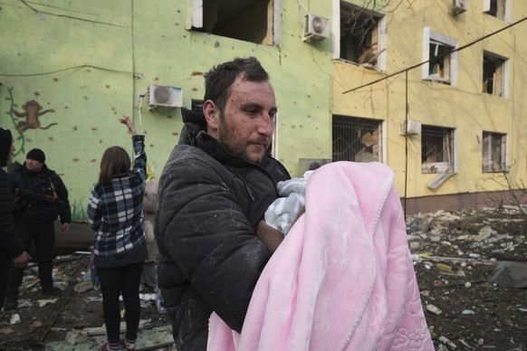 A man holds a baby during an evacuation from a maternity hospital damaged by a shelling attack in Mariupol, Ukraine, Wednesday, March 9, 2022. Associated Press journalists, who have been reporting fro ...