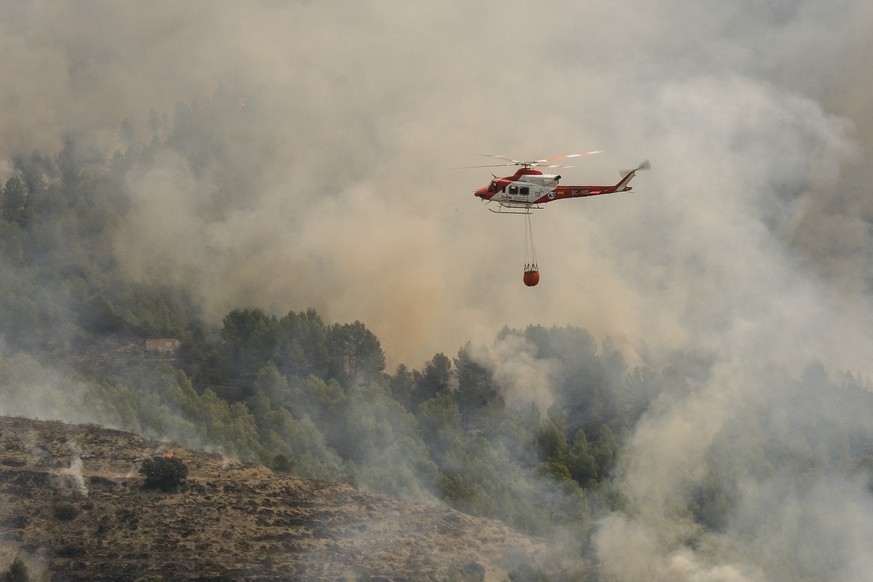epa11279837 A Spanish firefighting helicopter is seen during a forest fire that broke out in the town of Tarbena, Alicante, eastern Spain, 15 April 2024. Three firefighters were injured, some 180 resi ...