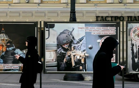 Des passants devant des affiches de propagande pour l'armée russe, qui cherche à recruter de nouveaux soldats. Ici dans une rue de Saint-Pétersbourg.