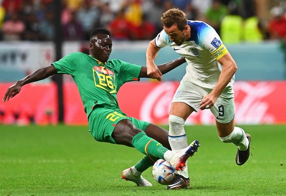 epa10348862 Harry Kane (R) of England in action against Pape Gueye (L) of Senegal during the FIFA World Cup 2022 round of 16 soccer match between England and Senegal at Al Bayt Stadium in Al Khor, Qat ...