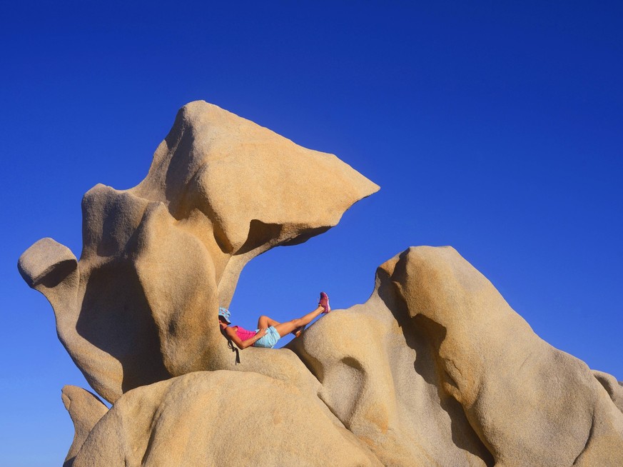 Frau sonnt sich auf bizarren Granitfelsen an der Kueste von Campomoro, Frankreich, Korsika, Propriano woman sunbathing at strange granite rock formation at the coast of Campomoro, France, Corsica, Pro ...