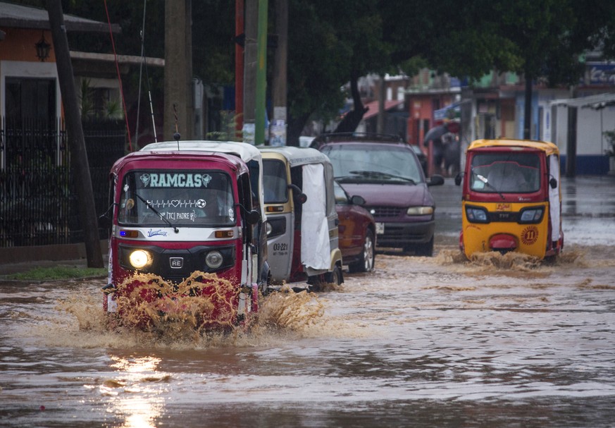 epa09987119 People transit through a flooded avenue in the municipality of Tehuantepec, Oaxaca state, Mexico, 30 May 2022. Hurricane Agatha, a category 2 storm formed in the Pacific, made landfall in  ...