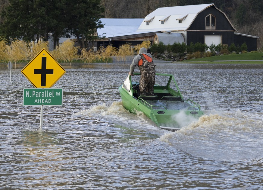 A man drives a boat down a flooded road in Chilliwack, British Columbia, Tuesday, Nov. 16, 2021. (Jonathan Hayward/The Canadian Press via AP)