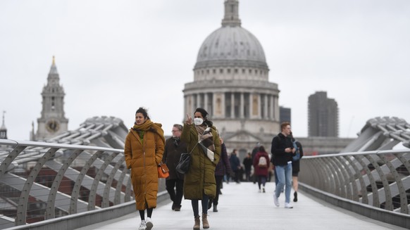 epa09774277 A woman wears a mask as she passes a view of St Paul's Cathedral in London, Britain, 20 February 2022. England is expected to end all Covid-19 restrictions in the coming days with people in England no longer having to self-isolate after a positive test, Downing Street has said.  EPA/NEIL HALL