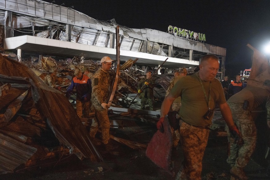 Volunteers work to take away debris at a shopping center burned after a rocket attack in Kremenchuk, Ukraine, early Tuesday, June 28, 2022. (AP Photo/Efrem Lukatsky)