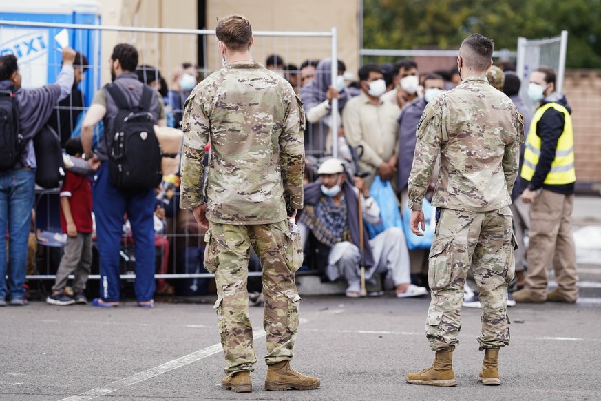 US soldiers stand in front of people evacuated from Afghanistan, at Ramstein Air Base, in Ramstein-Miesenbach, Germany, Monday, Aug. 30, 2021. The United States is using its military base in Ramstein, ...