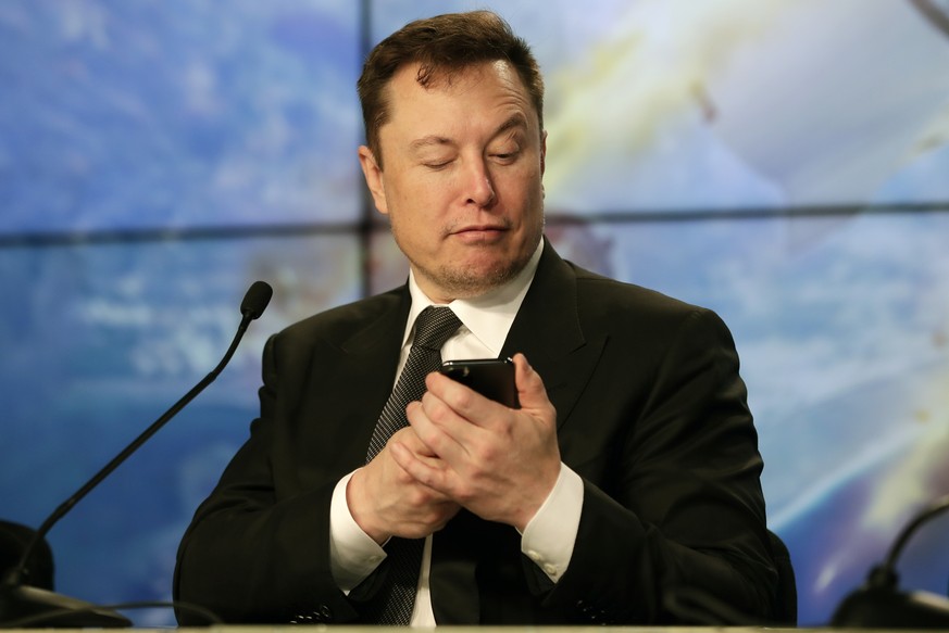 FILE - Elon Musk founder, CEO, and chief engineer/designer of SpaceX jokes with reporters as he pretends to search for an answer to a question on a cell phone during a news conference after a Falcon 9 ...