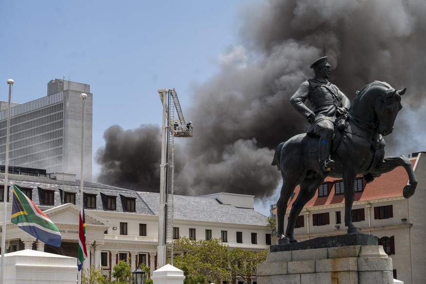 Firemen spray water on flames erupting from a building at South Africa's Parliament in Cape Town Sunday Jan. 2, 2022. (AP Photo/Jerome Delay)
