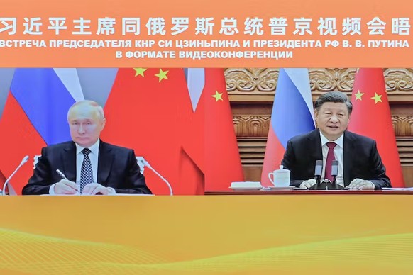 Sur cette photo publiée par l’agence de presse Xinhua, le président chinois Xi Jinping (à droite) et le président russe Vladimir Poutine apparaissent à l’écran lors d’une réunion par liaison vidéo à P ...