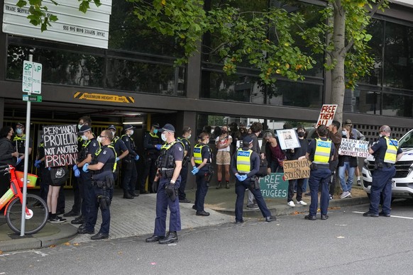 Police surround refugee advocates at the Park Hotel, used as an immigration detention hotel where Serbian tennis player Novak Djokovic is confined in Melbourne, Australia, Monday, Jan. 10, 2022. After ...