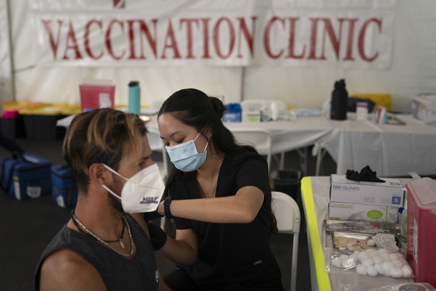 FILE - Registered nurse, Noleen Nobleza, center, inoculates Julio Quinones with a COVID-19 vaccine at a clinic set up in the parking lot of CalOptima in Orange, Calif., on Aug. 28, 2021. The fate of P ...