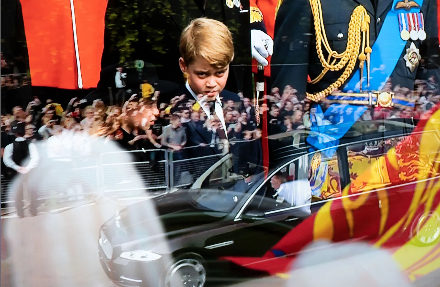 Photographié à partir d'un écran de télévision, le cercueil de la reine Elizabeth dans le corbillard d'État est conduit à Windsor devant des foules bordant la route avec le prince George, en arrière-p ...