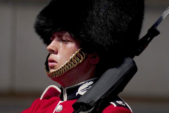 A member of F Company Scots Guards swelters in the heat during the Changing of the Guard ceremony on the forecourt of Buckingham Palace, central London, Tuesday July 19, 2022. Millions of people in Br ...