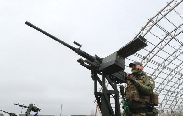 epa10553625 A Ukrainian serviceman handles a machine gun during the handing over of ten pick-up trucks to mobile anti-drone units near the largest Ukrainian cargo aircraft Antonov An-225 Mriya &#039;D ...