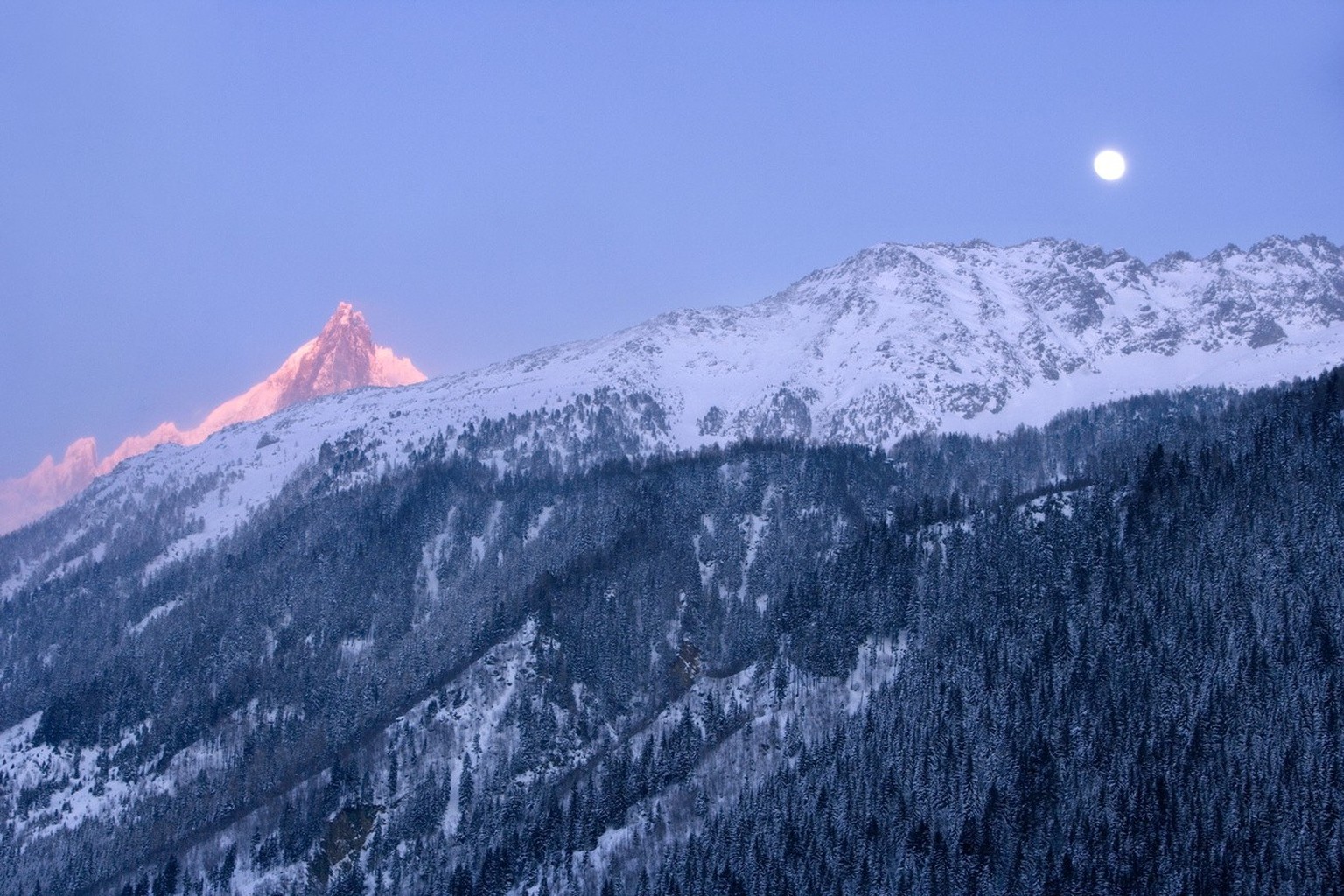 Der Vollmond im Abendlicht ueber dem Mont Blanc-Massiv bei Chamonix, Frankreich, am 12. Maerz 2006. (KEYSTONE/Martin Ruetschi)