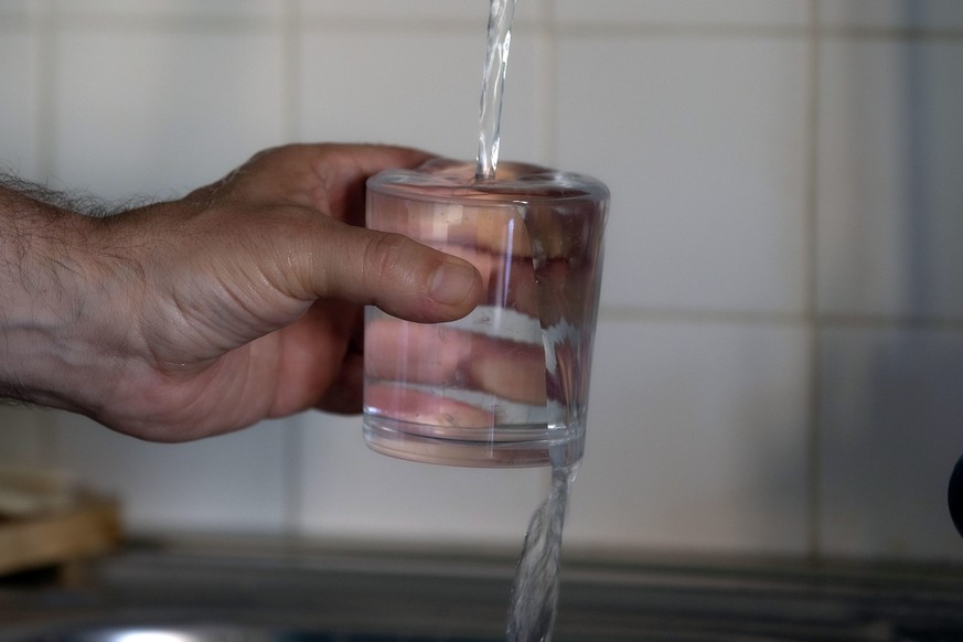 epa10023981 A man fills a glass with tap water, in Rome, Italy, 20 June 2022. Lazio on 20 June declared a state of calamity for drought that has hit the central Italian region and many others, especia ...
