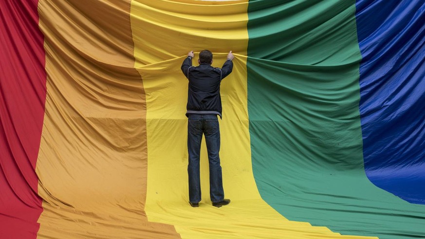 Swiss LGBT activists prepare a flag during a vigil for those killed and wounded in the Sunday June 12, mass shooting at a gay nightclub in Orlando, at a church in Zuerich, Switzerland, Monday, June 13 ...