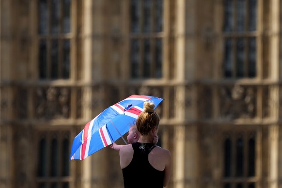 A mother shelters her baby from the sun with an umbrella on Westminster Bridge in London, Tuesday, July 19, 2022. Britain shattered its record for highest temperature ever registered amid a heat wave ...