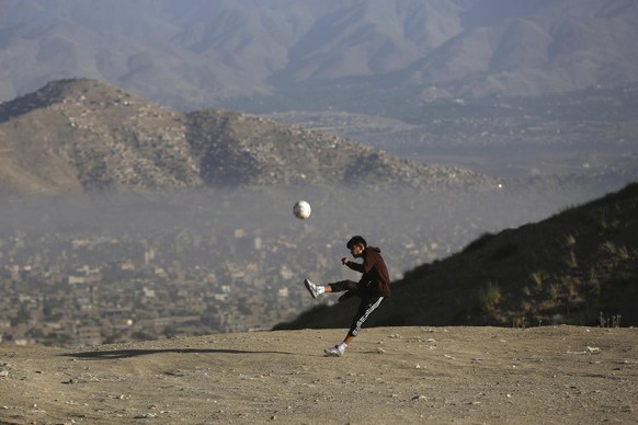 An Afghan young boy plays football amid the COVID-19 pandemic lockdown, on the outskirts of Kabul, Afghanistan, Sunday, June 21, 2020. (AP Photo/Rahmat Gul)